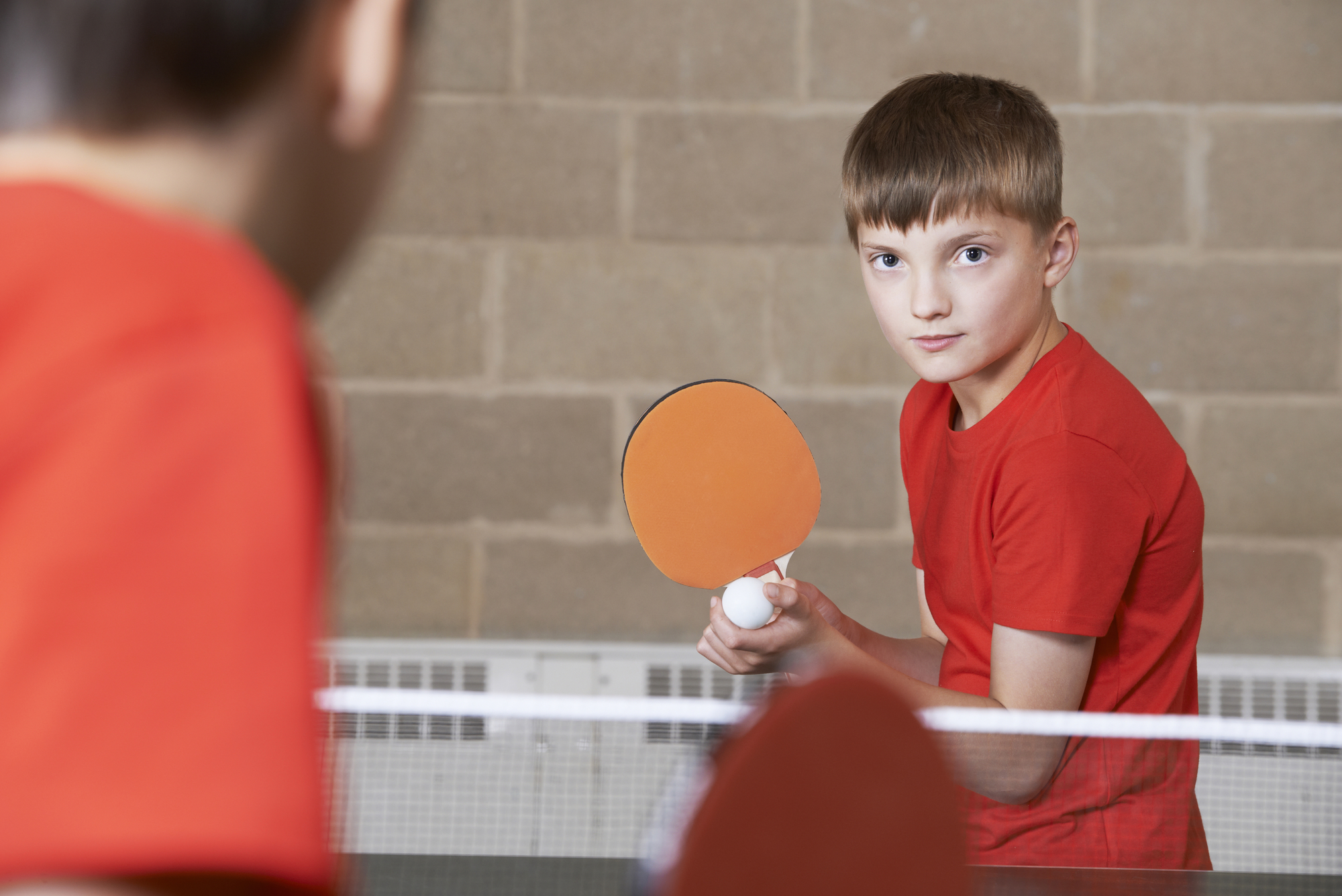 Two Boys Playing Table Tennis Match In School Gym